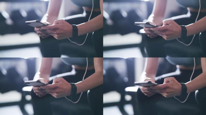 年轻女运动员在健身房听音乐时使用智能手机