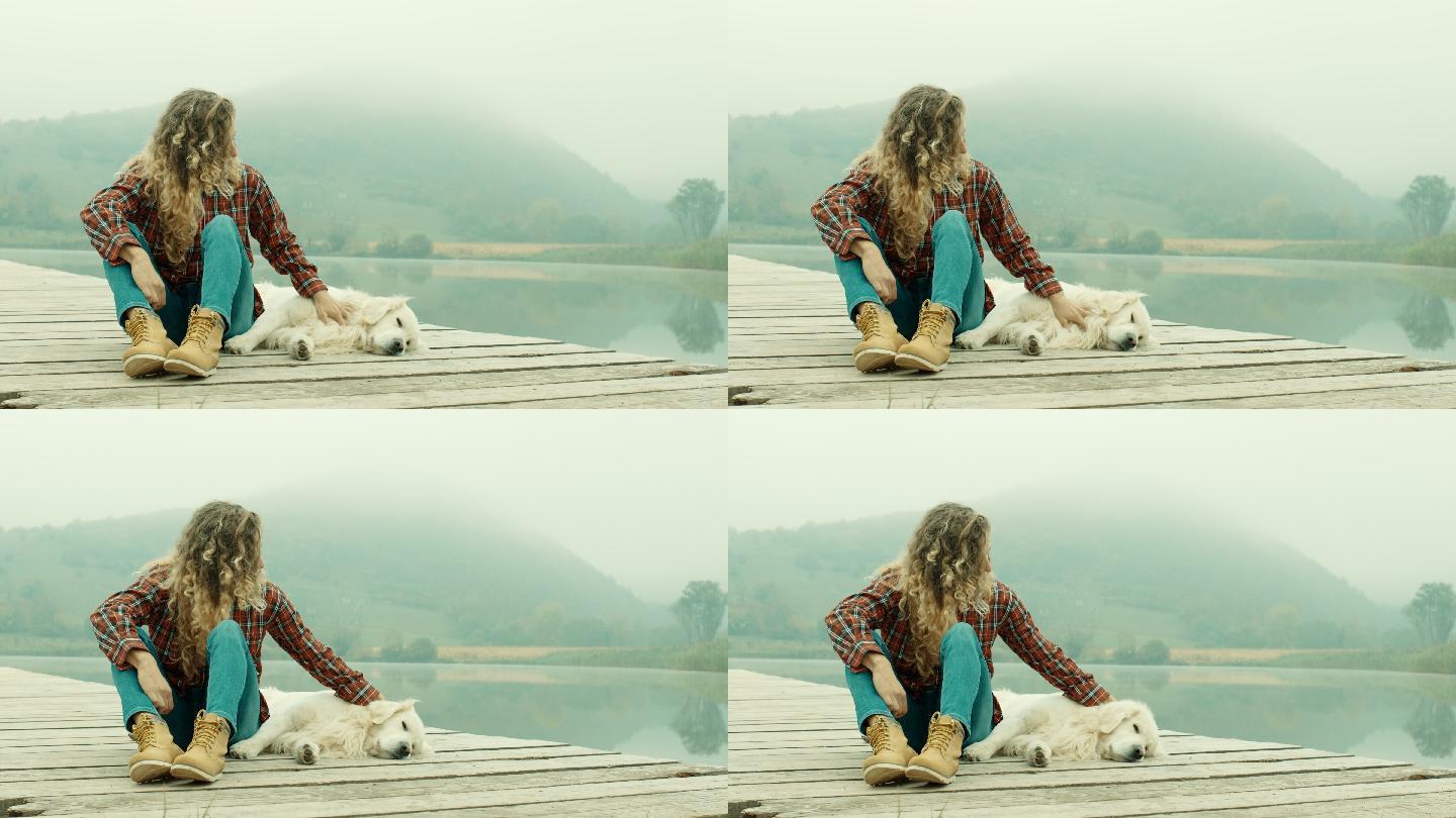 年轻女子和狗一起在湖边的码头
