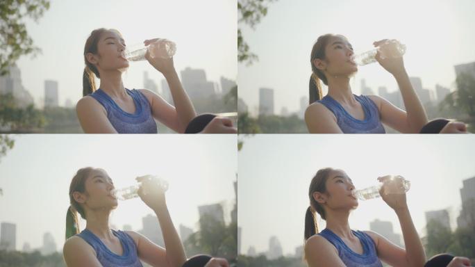 女子一边在户外运动一边对着夕阳喝水