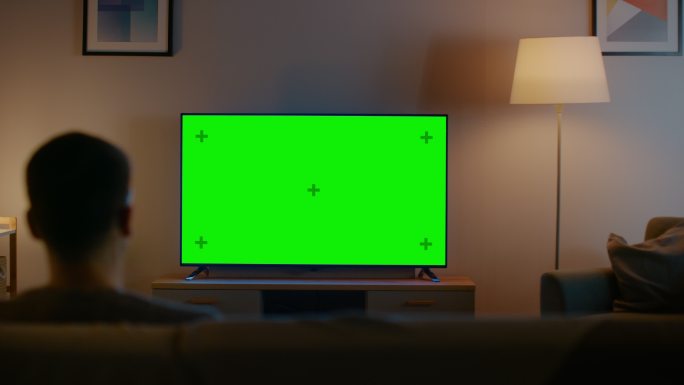 年轻人在沙发上看绿色屏幕模型电视