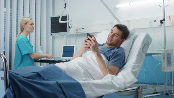 康复中的患者躺在医院的病床上使用智能手机