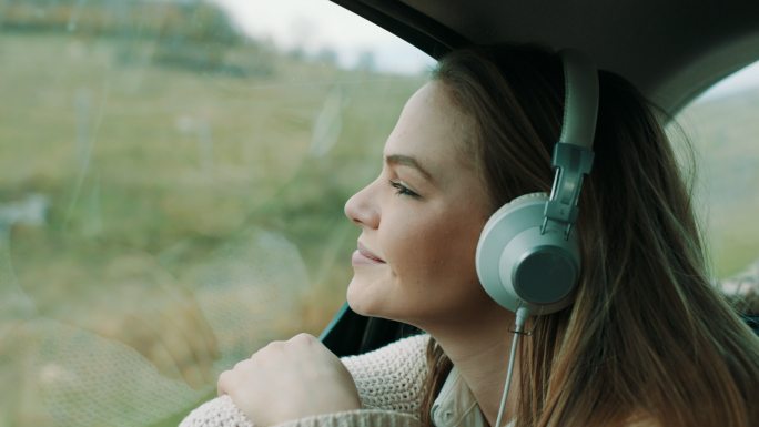 坐在汽车后座听音乐的女孩