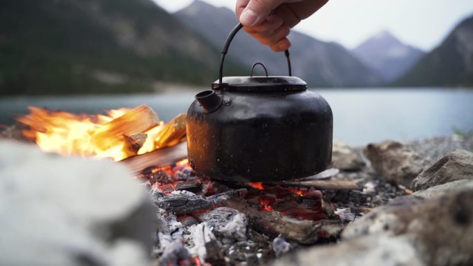 把水壶放在山湖附近的户外篝火上