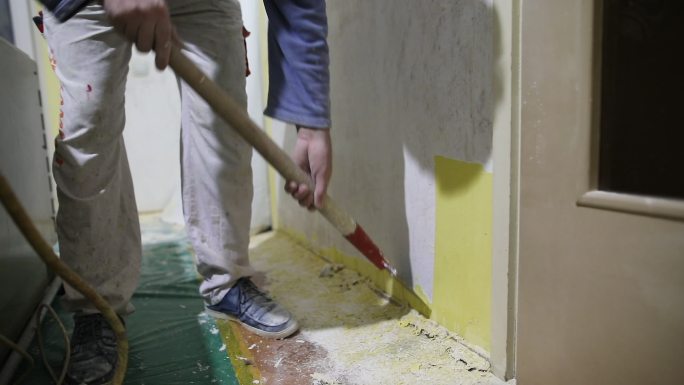 家装工人用刮刀清除旧的黄色油漆