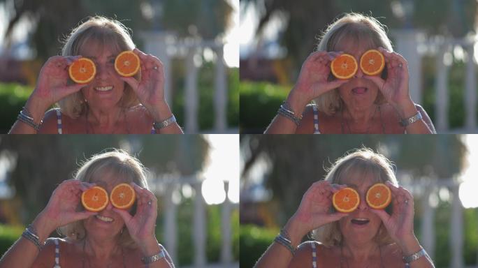 站在阳光下的成熟女人拿着两片橙子