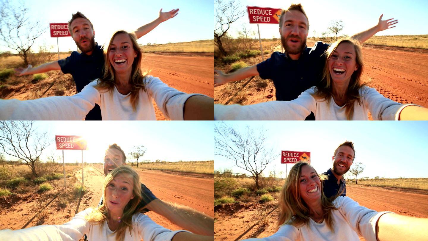 年轻夫妇站在骆驼警告牌旁自拍