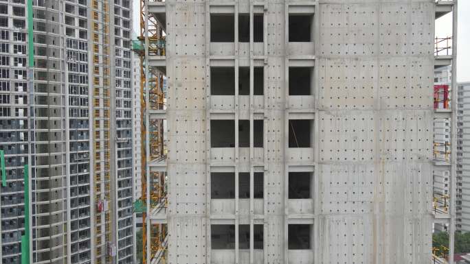 鸟瞰无人机在建筑工地的摩天大楼周围飞行
