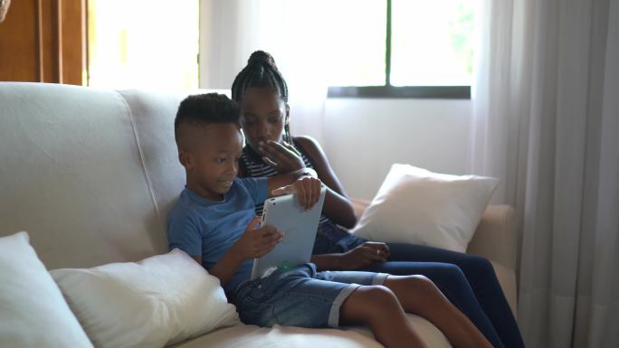 兄弟姐妹在数字平板电脑或电子阅读器上阅读