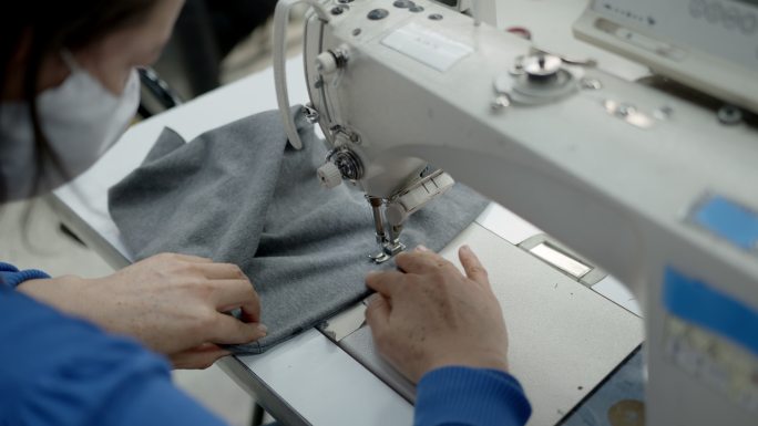 在纺织厂缝制连帽衫的一名妇女的特写镜头
