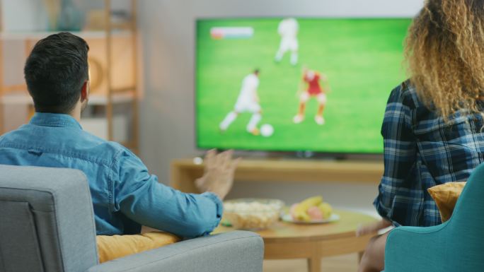 年轻夫妇在电视上观看足球比赛