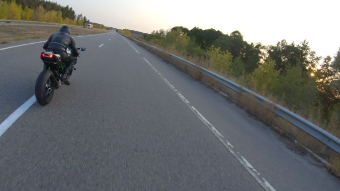 日落时分，跟随骑在乡村公路上的摩托车手。