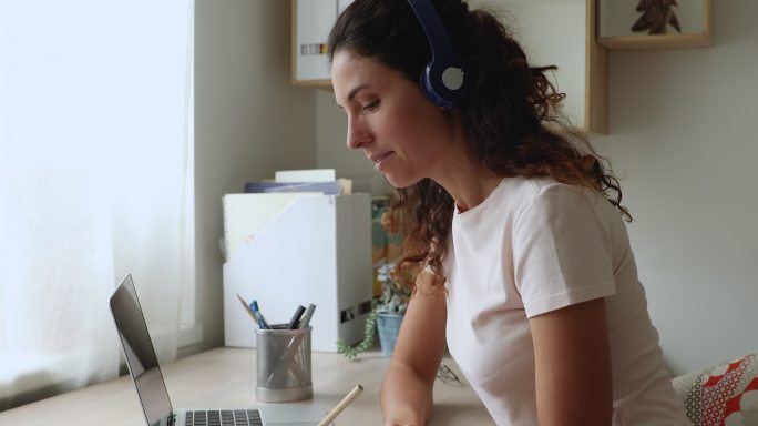 戴着耳机在网上上课的快乐年轻女子。