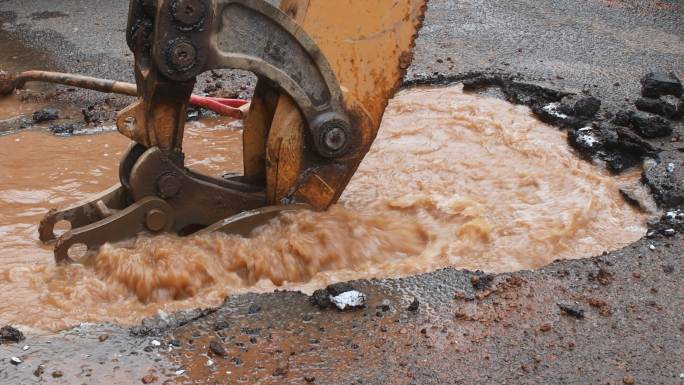 水管破裂，从道路上的一个洞里漏水