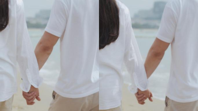 夫妇手牵手在海滩上散步