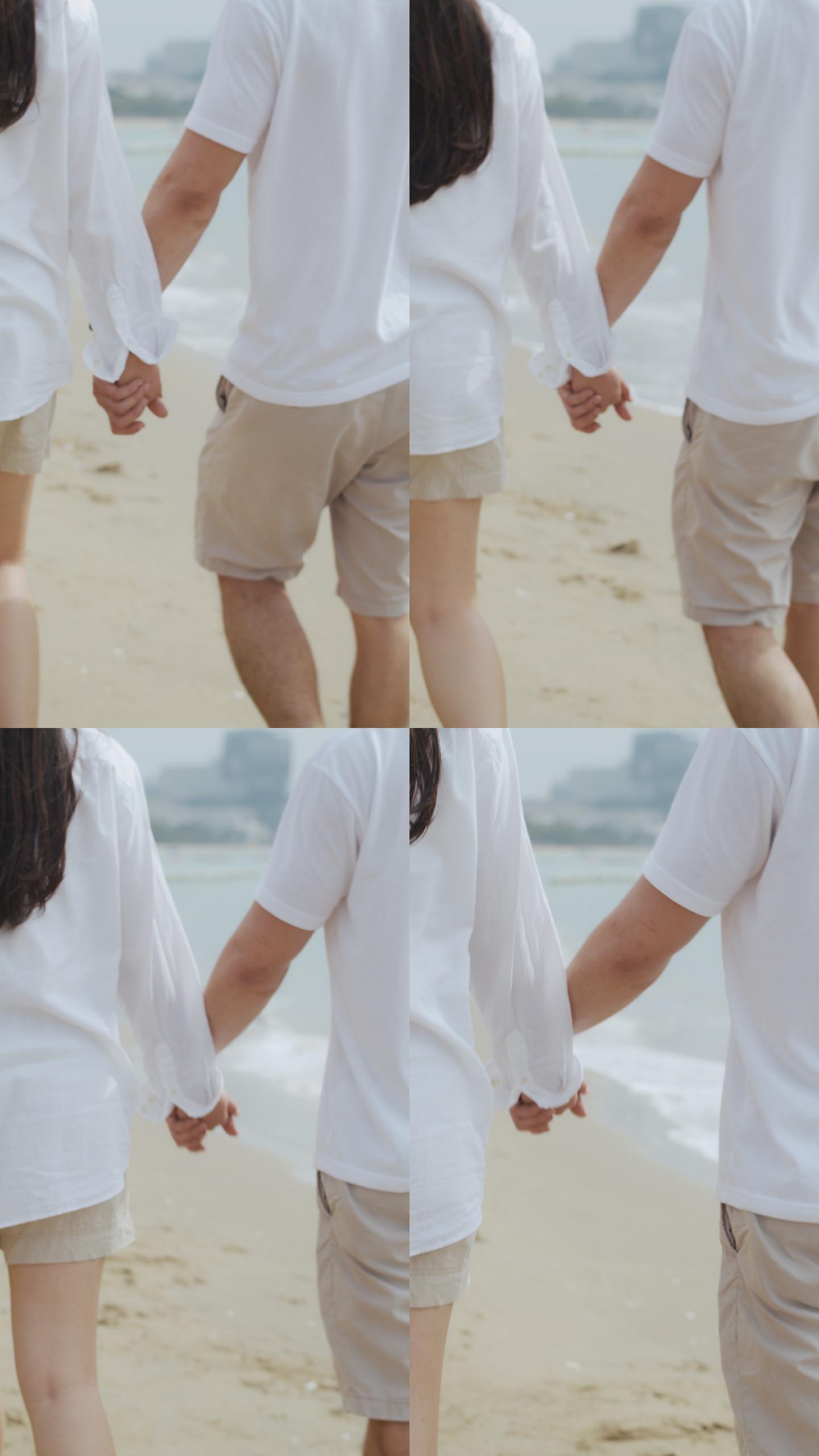 夫妇手牵手在海滩上散步