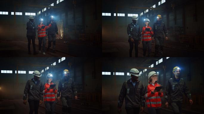 三重工业工程师在黑暗的钢铁厂里行走。