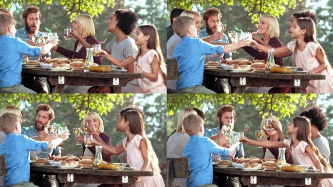 阳光明媚的日子里，一家人在野餐桌上碰杯