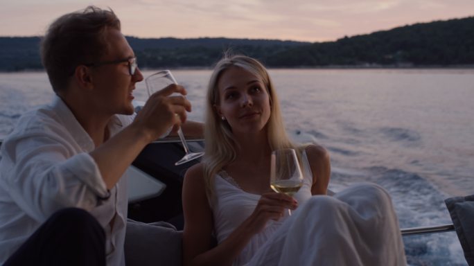 这对年轻夫妇在游艇的船尾聊天，喝香槟。