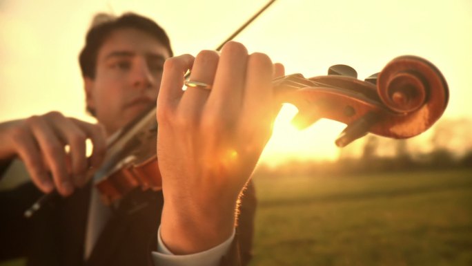 年轻人站在户外草地上激情地拉小提琴