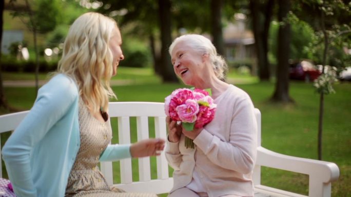 女儿带着鲜花和礼物送给年长的母亲