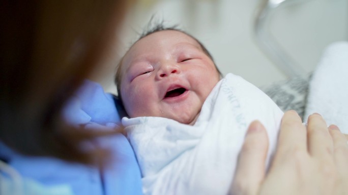 女性在医院病床上抱着新生儿