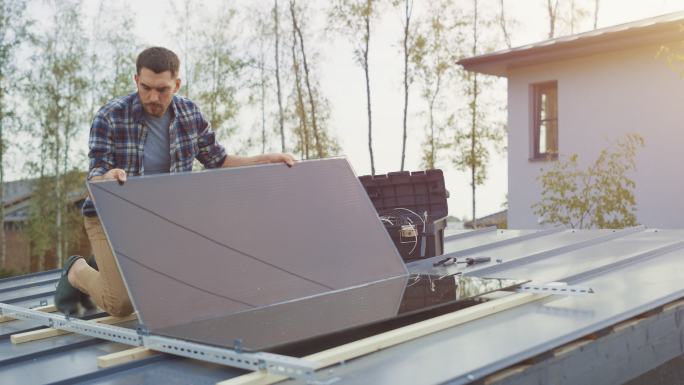 一名男子在屋顶上安装太阳能电池板。