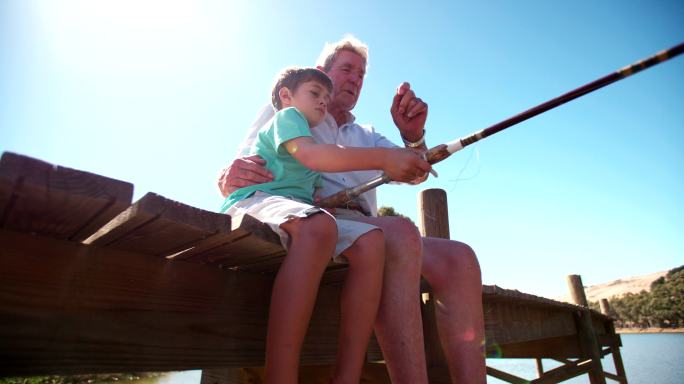 退休的祖父教他的孙子钓鱼