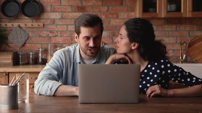 微笑真诚的年轻夫妇在家里使用电脑。