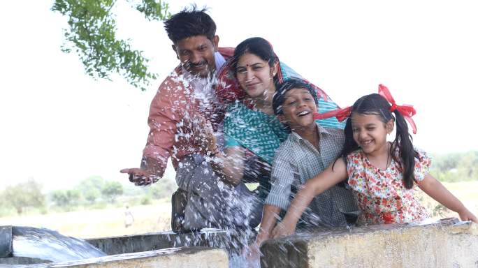 家庭在农田里用水管泼水玩得很开心