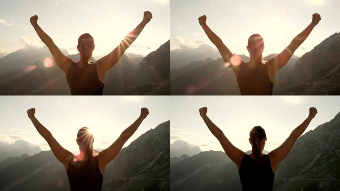 特写镜头：年轻女子举起双手站在山的边缘
