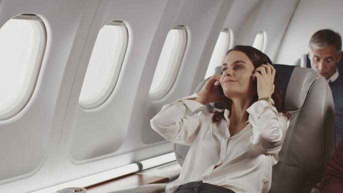 在私人飞机上戴耳机的女商人