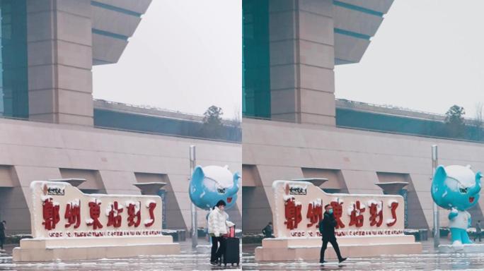 竖屏下雪后郑州东站旅客带着行李进出高铁站