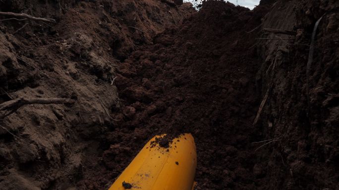 将泥土倾倒到覆盖有保护套管的黄色管道上