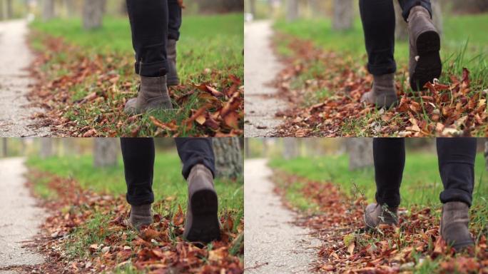 穿着皮鞋的年轻人正沿着一条落叶路走着。
