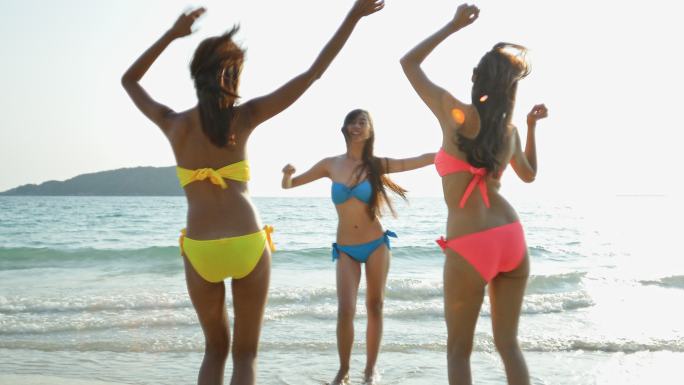 三个美丽的女人在海滩上快乐地跳舞。