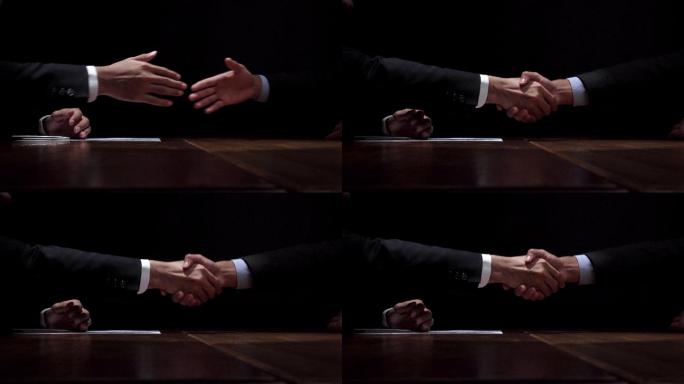商务伙伴在暗室秘密会面后握手