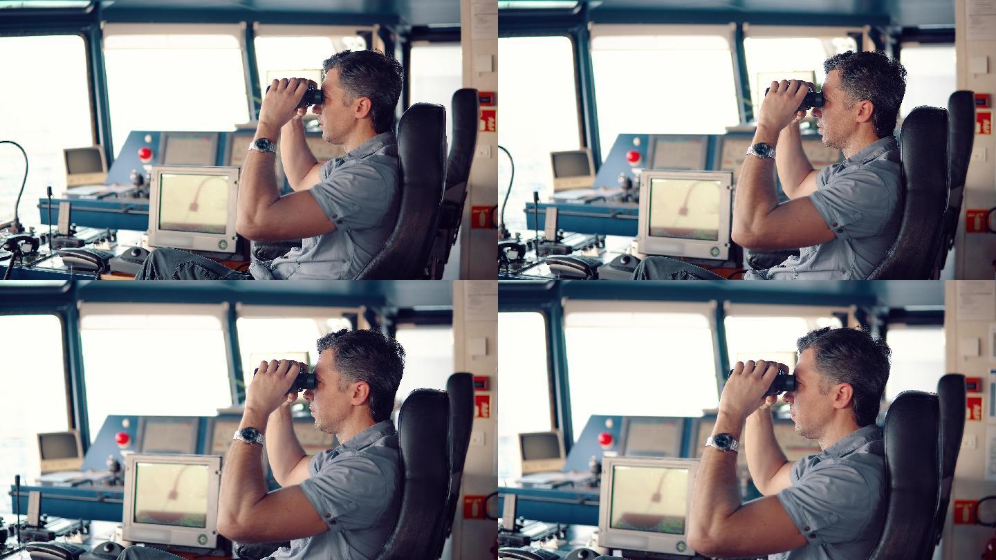 航海官在航海值班台上通过双筒望远镜观察。