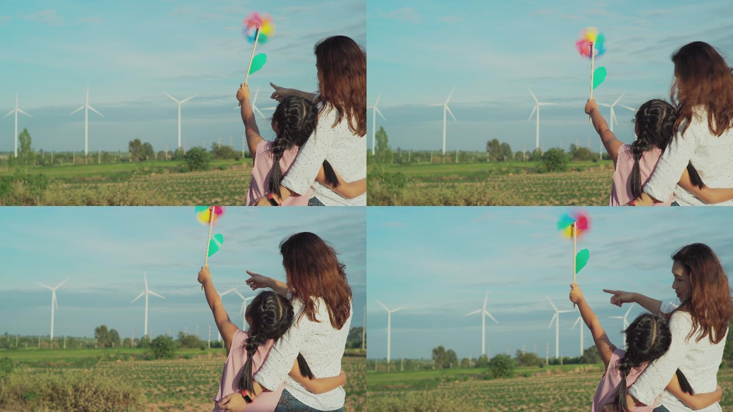 母亲和女儿在风力发电场玩耍