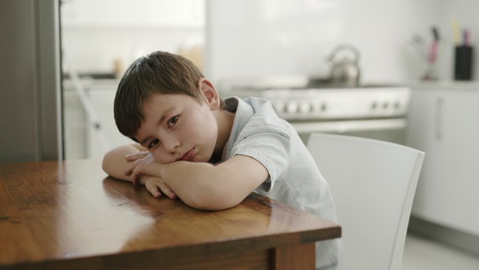 一个可爱的小男孩坐在厨房的桌子旁