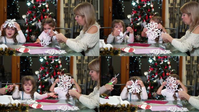 母亲和孩子们在圣诞树上剪纸雪花