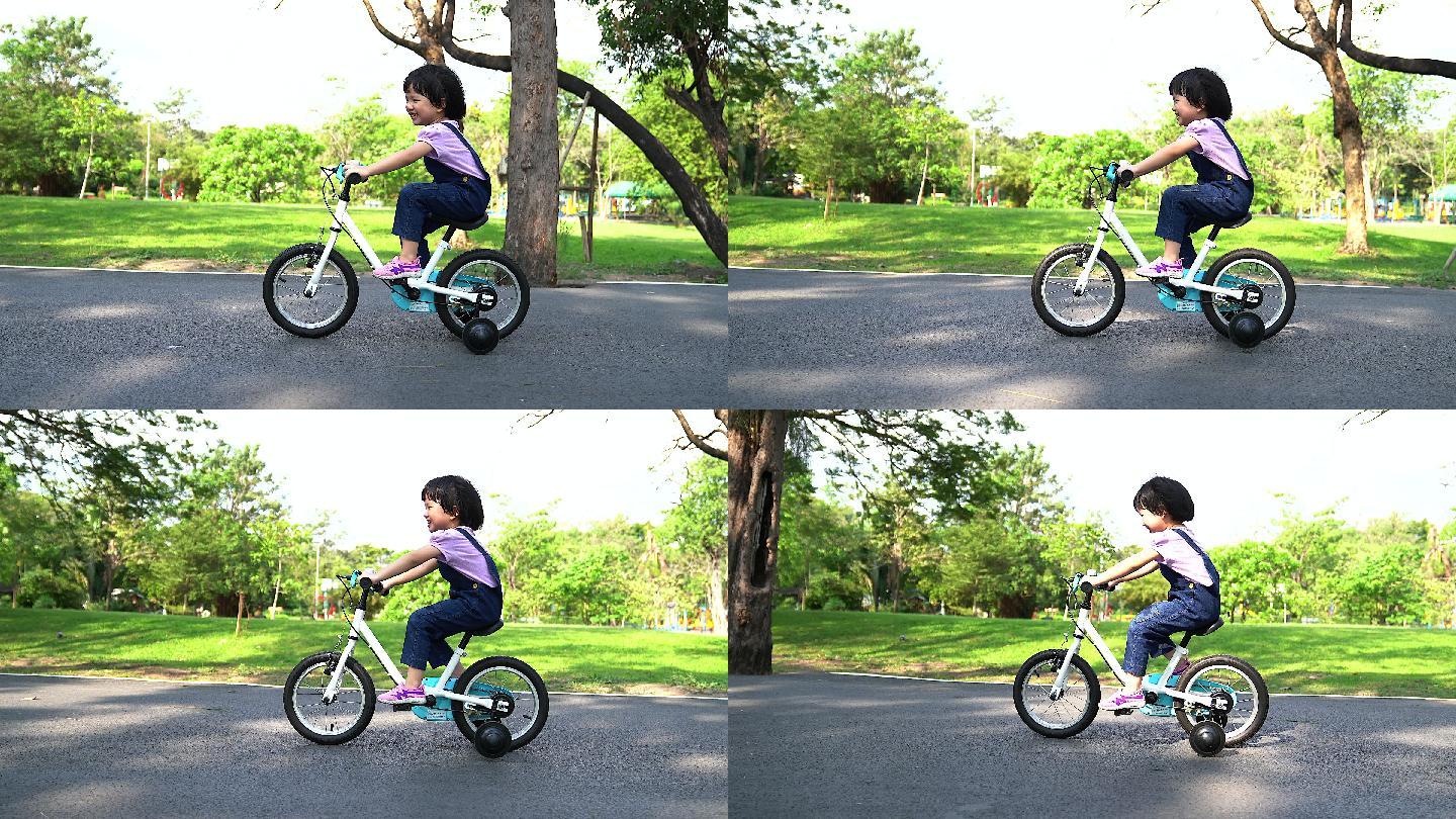 在阳光明媚的公园里骑自行车的小女孩。