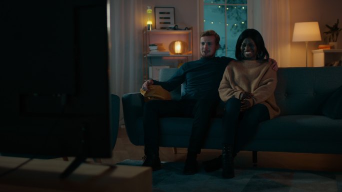 年轻夫妇坐在沙发上看电视电影