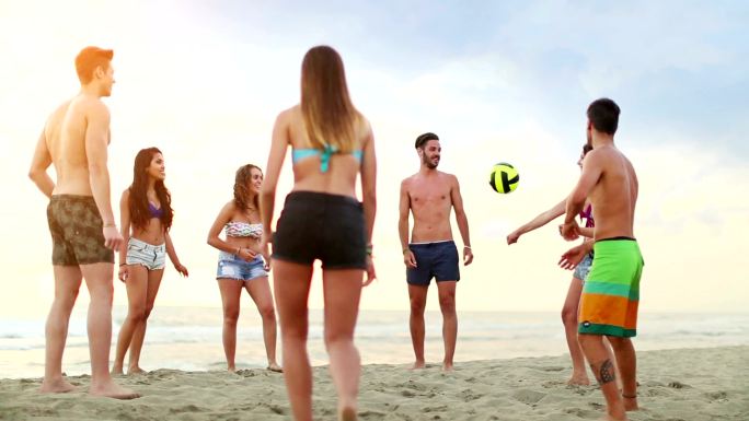 在沙滩上玩排球的一群人