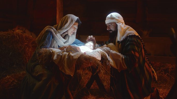 玛丽和约瑟夫在发光的马槽里爱抚着小耶稣