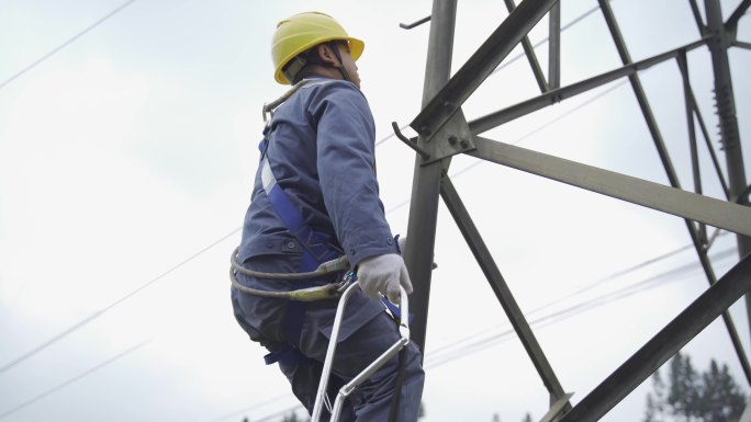 正在攀爬上电塔的电力维修工，高空作业。