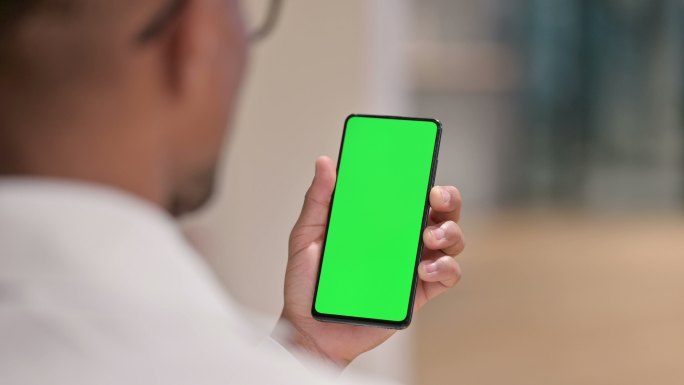 男医生使用绿屏智能手机的后视图