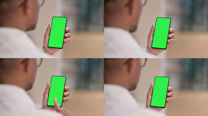 男医生使用绿屏智能手机的后视图