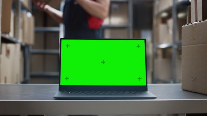 绿色模拟屏幕的笔记本电脑放在仓库的桌面