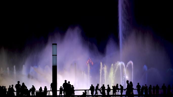 夜晚看喷泉的人彩色喷泉