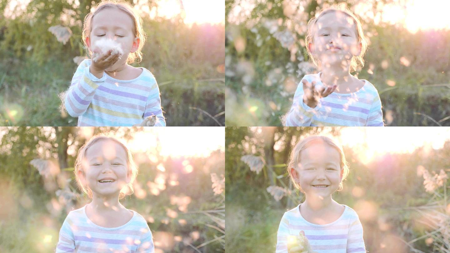 可爱的小女孩享受吹蒲公英种子的乐趣。